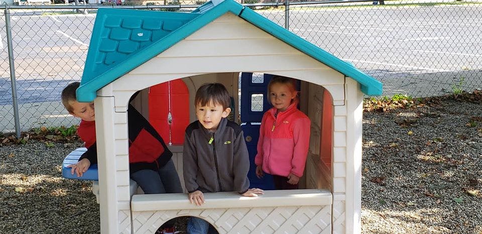Three children playing in a small playhouse