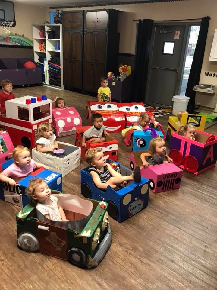 Children sitting in cardboard box cars in a room