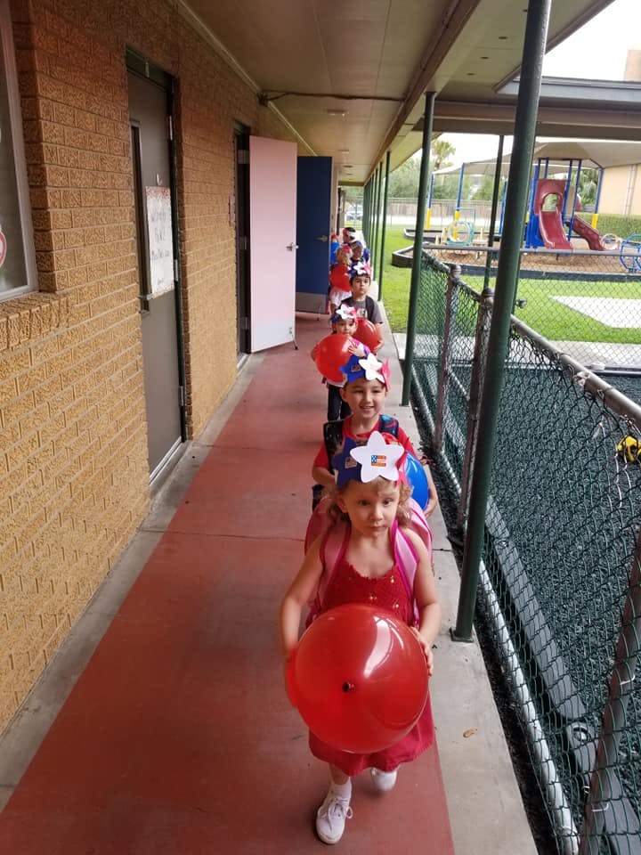 Children in a line on a covered walkway, wearing star headbands
