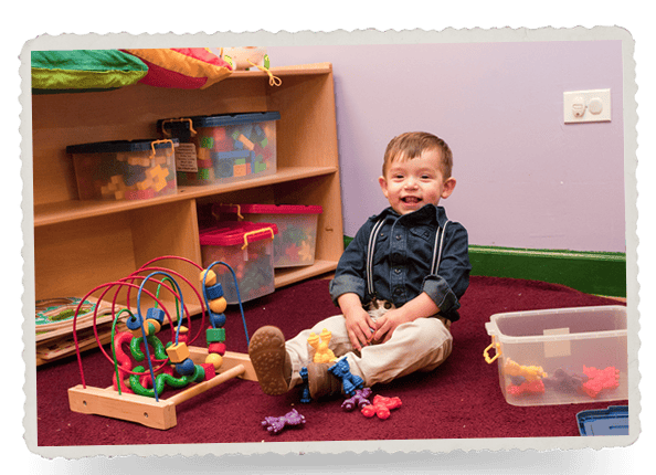 Child sitting on floor with toys in a classroom