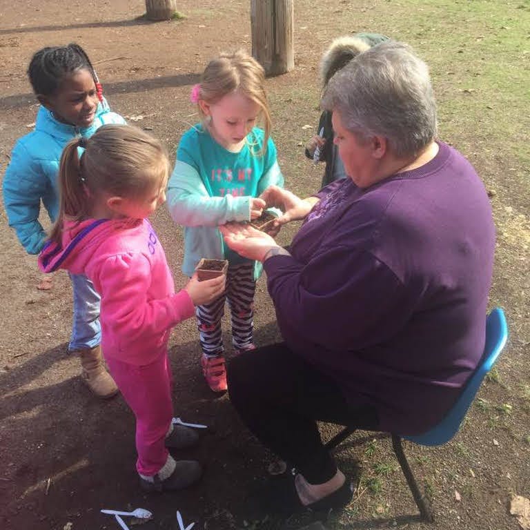 Adult and three children planting seeds outdoors