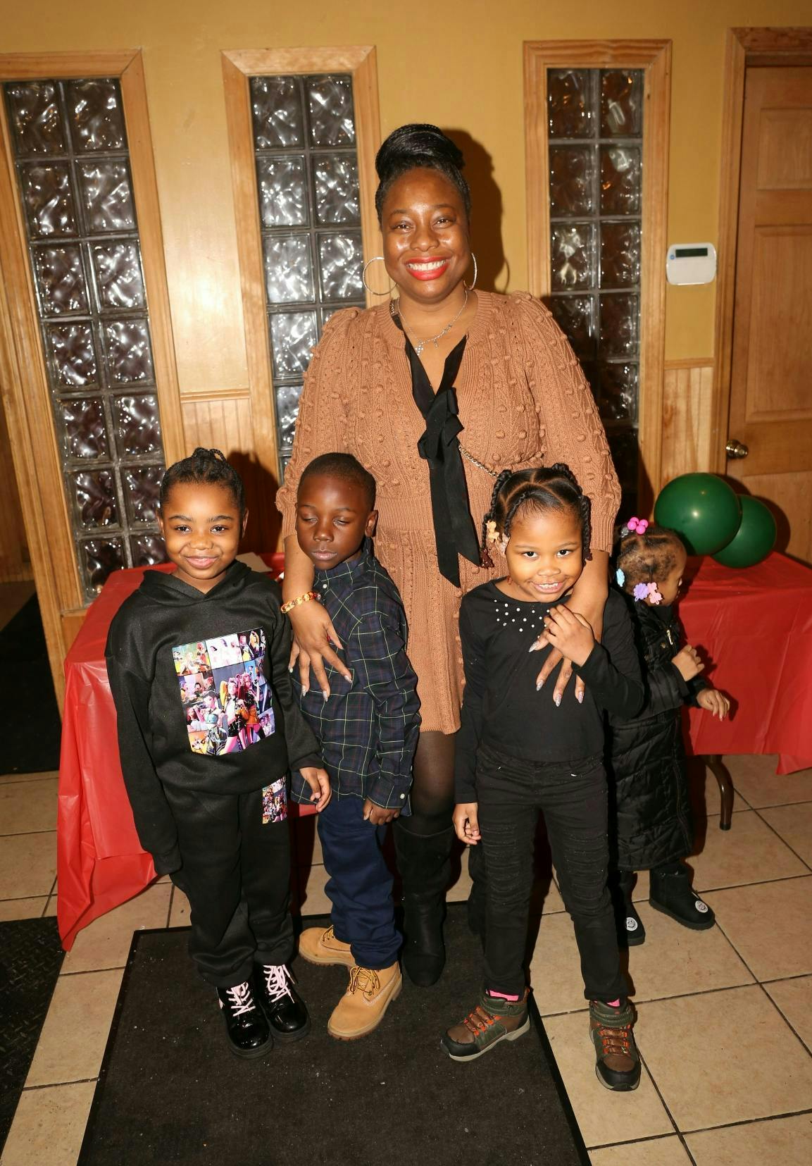 Person standing with four children, one child looks away