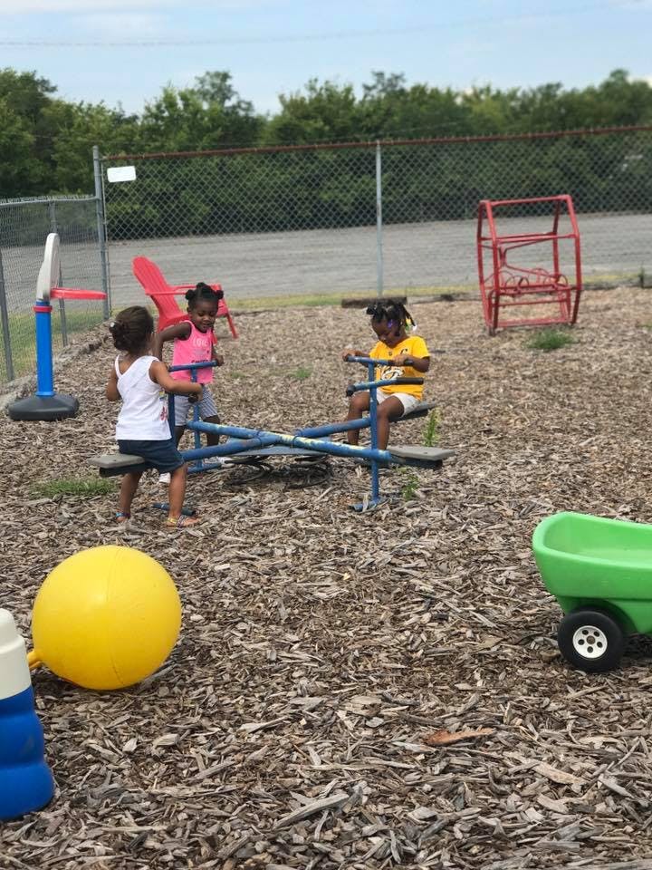 Three children playing on a seesaw in a playground