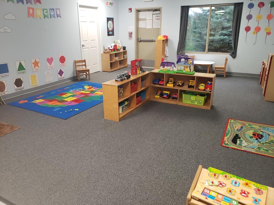 Empty classroom with shelves of toys and colorful rugs