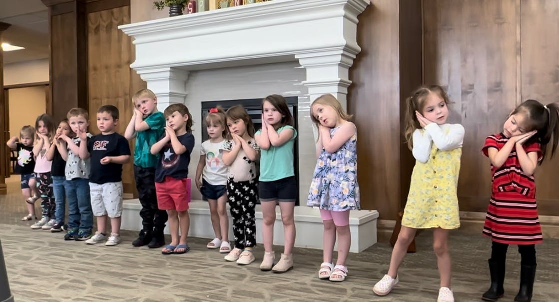 Group of children standing with hands together under their chins