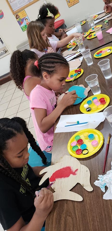 Children painting wooden cutouts at a table