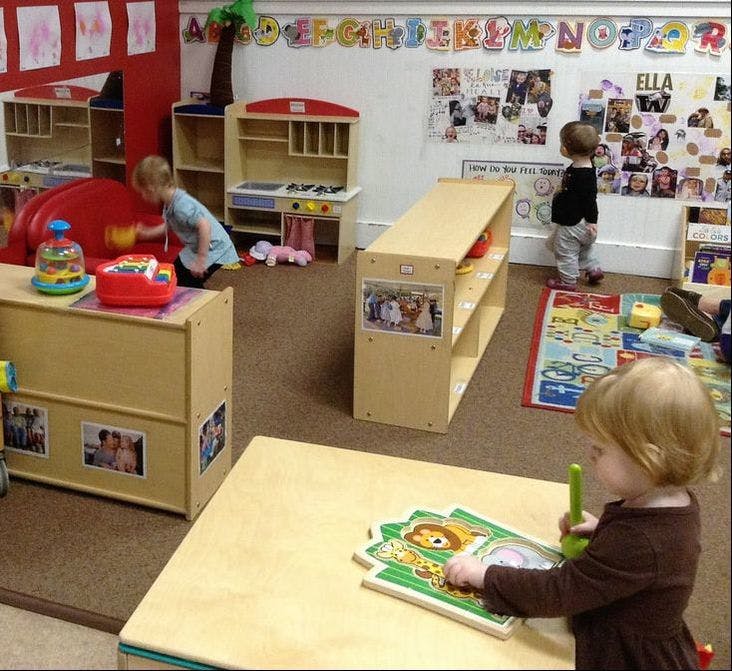 Children playing in a classroom with toys and puzzles