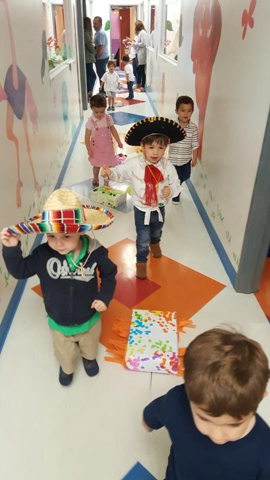 Children in a hallway, some wearing sombreros