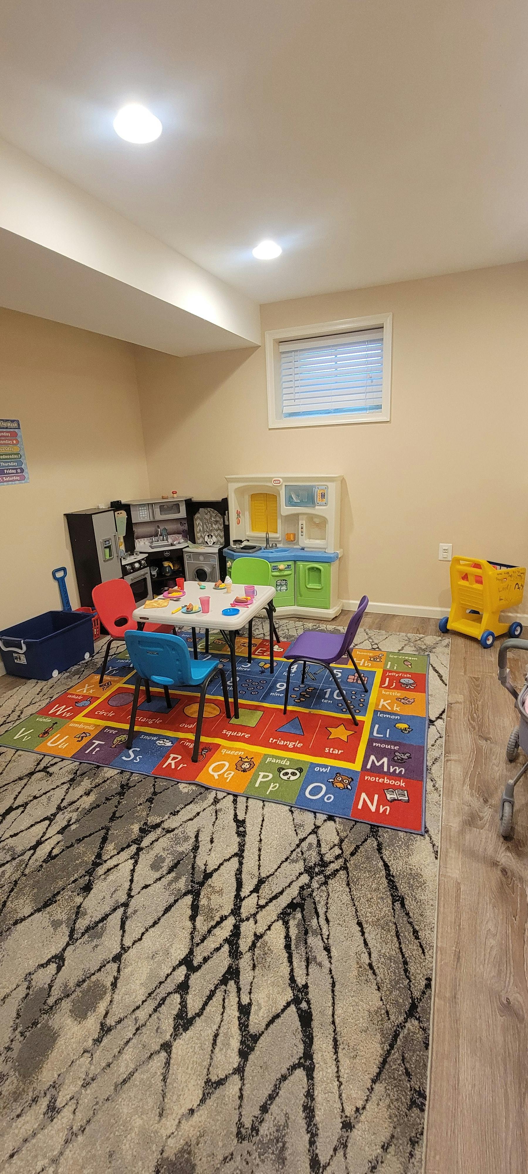 Playroom with a plastic toy kitchen and small table with chairs on a rug