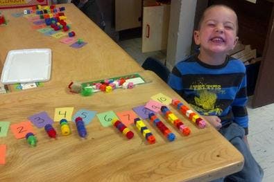 Child at a table with colorful counting blocks and numbered cards