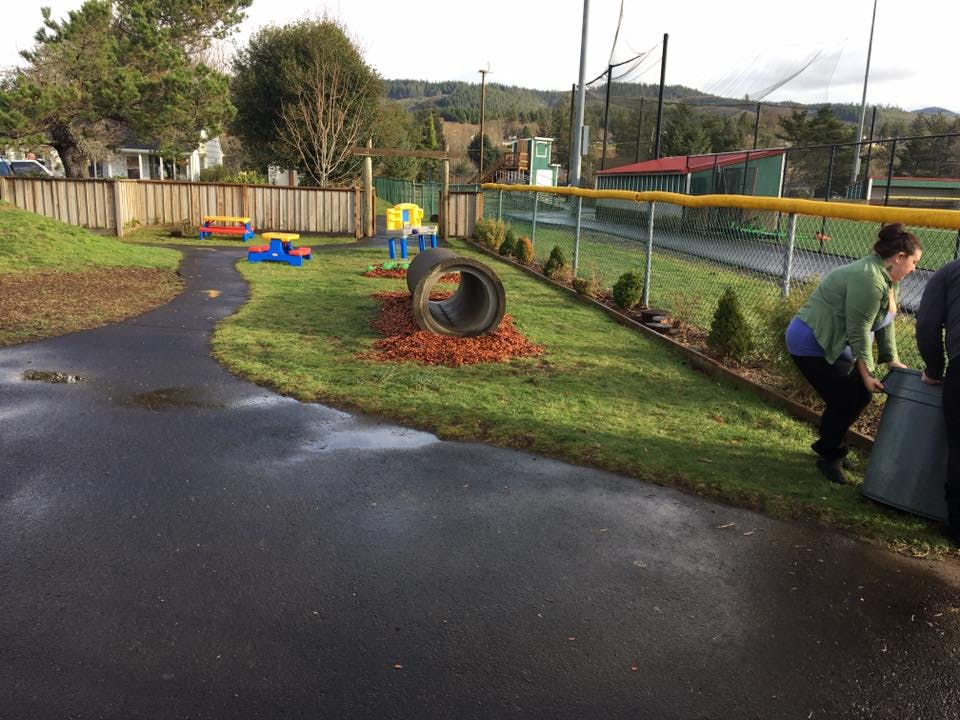 Person bending over next to a large container on a paved path