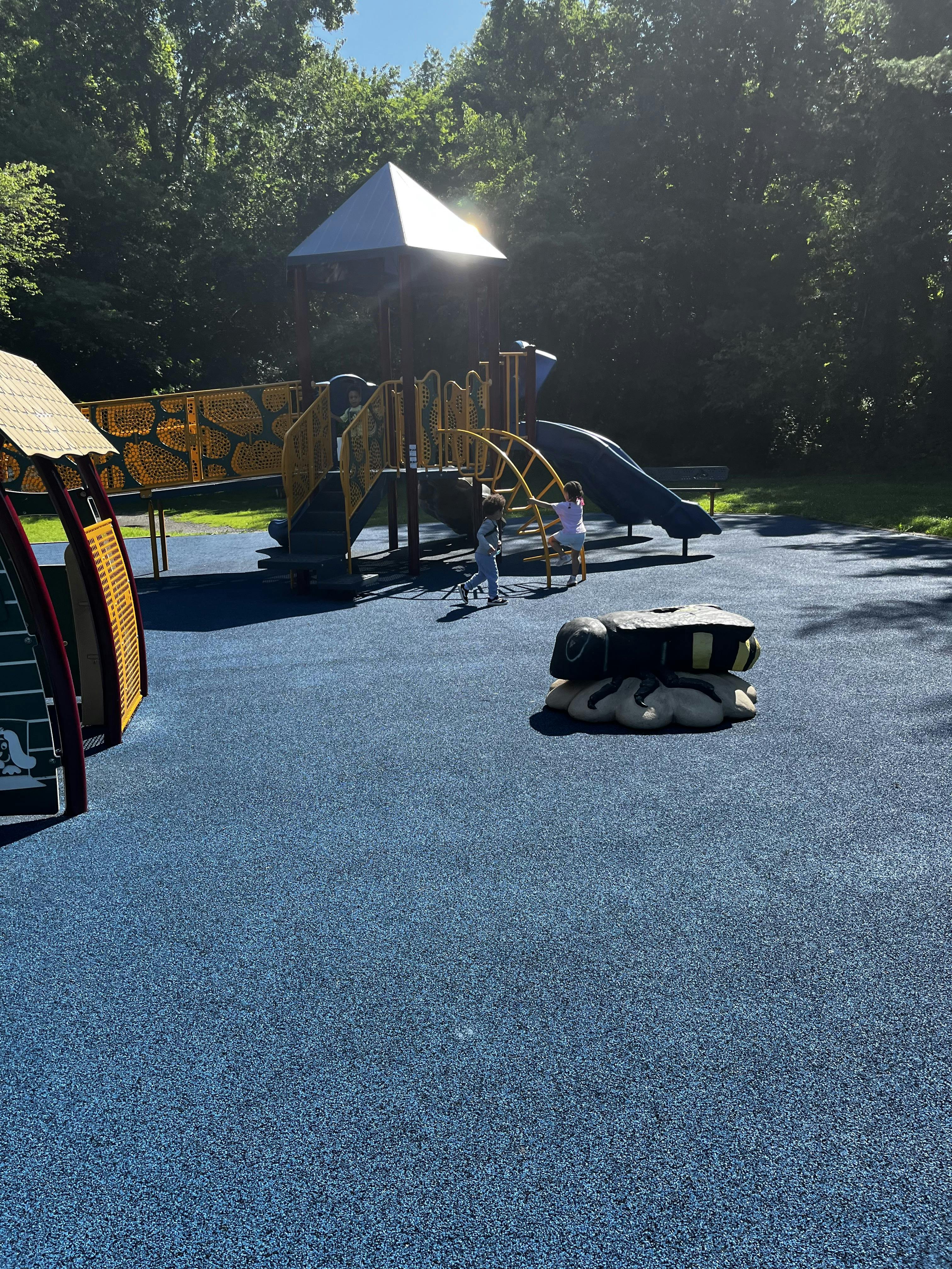 Two children playing on a playground structure with slides and climbing structures