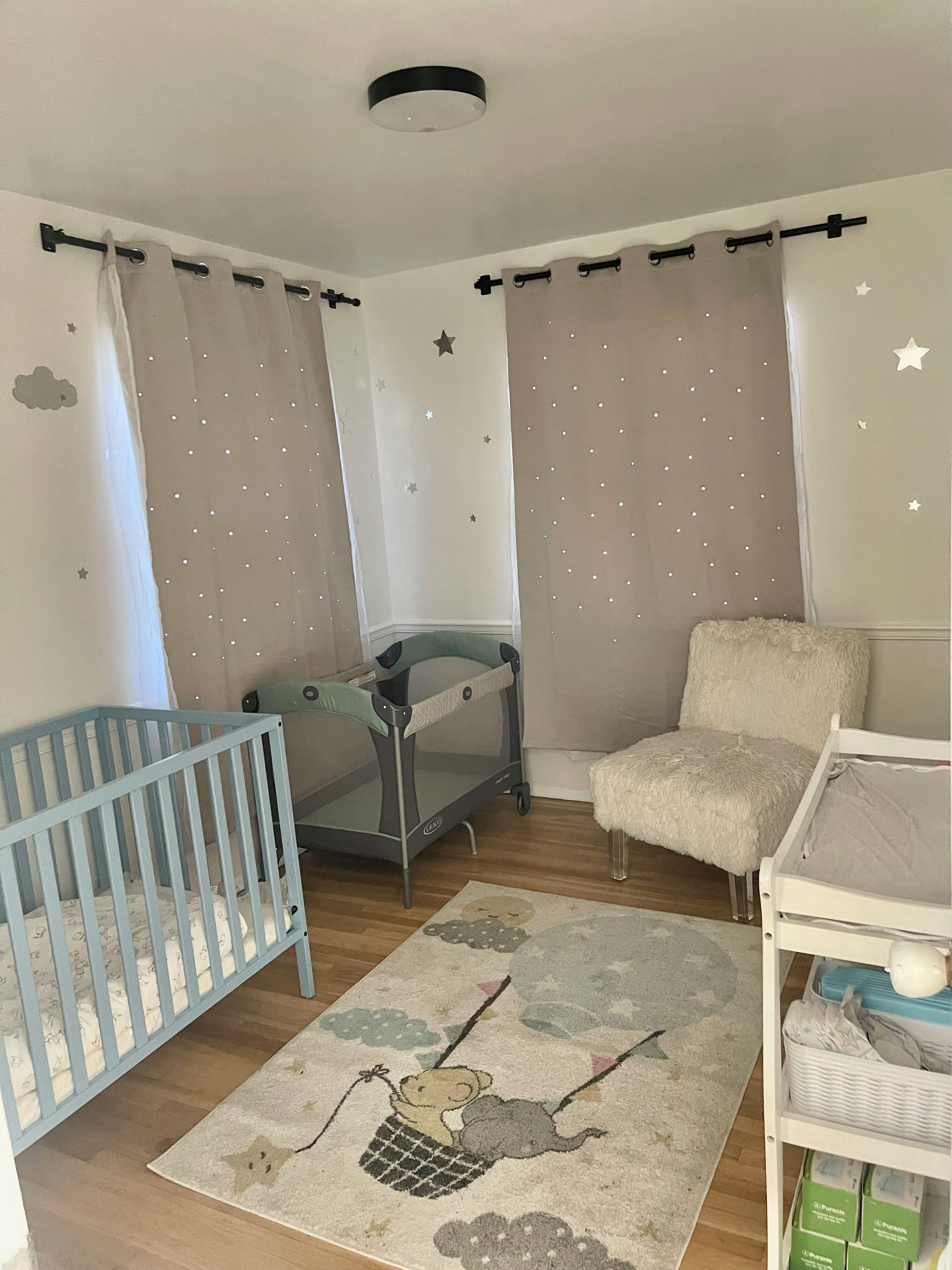 Nursery room with a blue crib, playpen, changing table, and rug