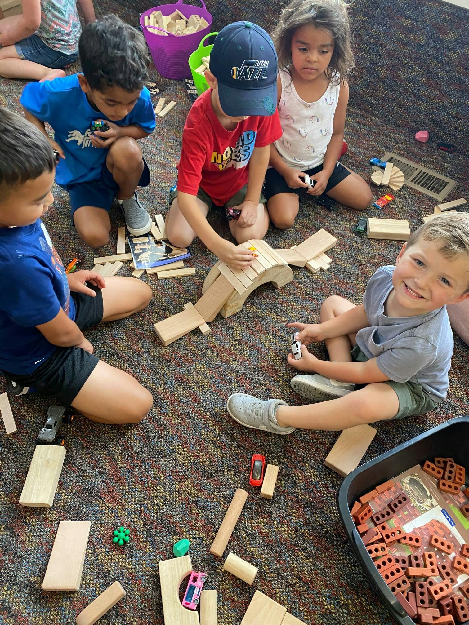 Children playing on the floor with wooden blocks and toy cars