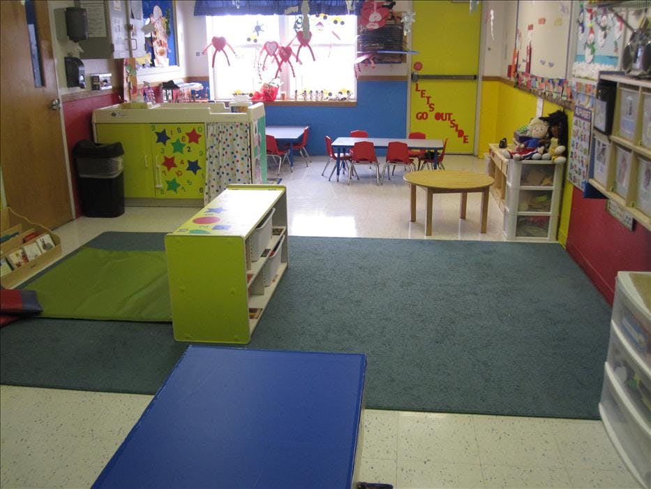 Empty colorful classroom with small tables, chairs, and shelves
