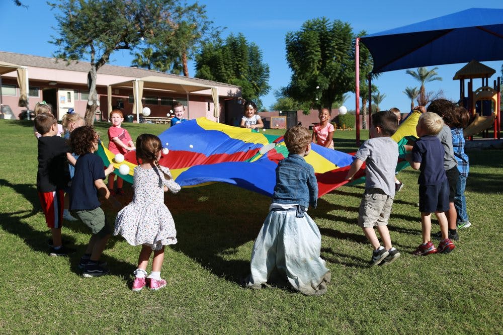 Children playing with a colorful parachute on a grassy field