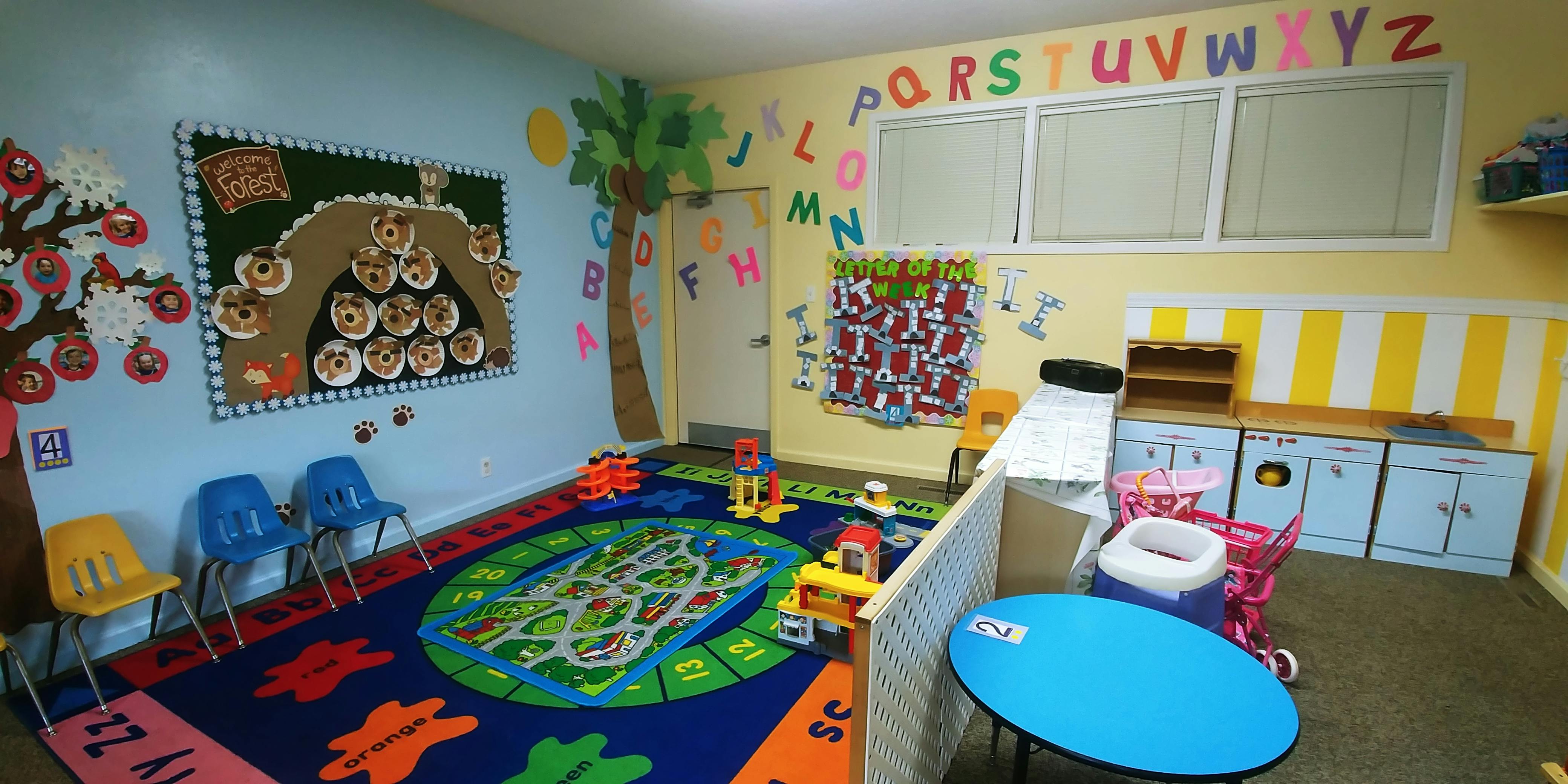 Playroom with colorful rug, small chairs, and alphabet letters on the wall