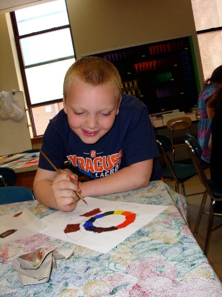 Child painting a colorful circle on paper with a paintbrush