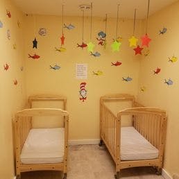 Two cribs in a room with wall decals and hanging decorations