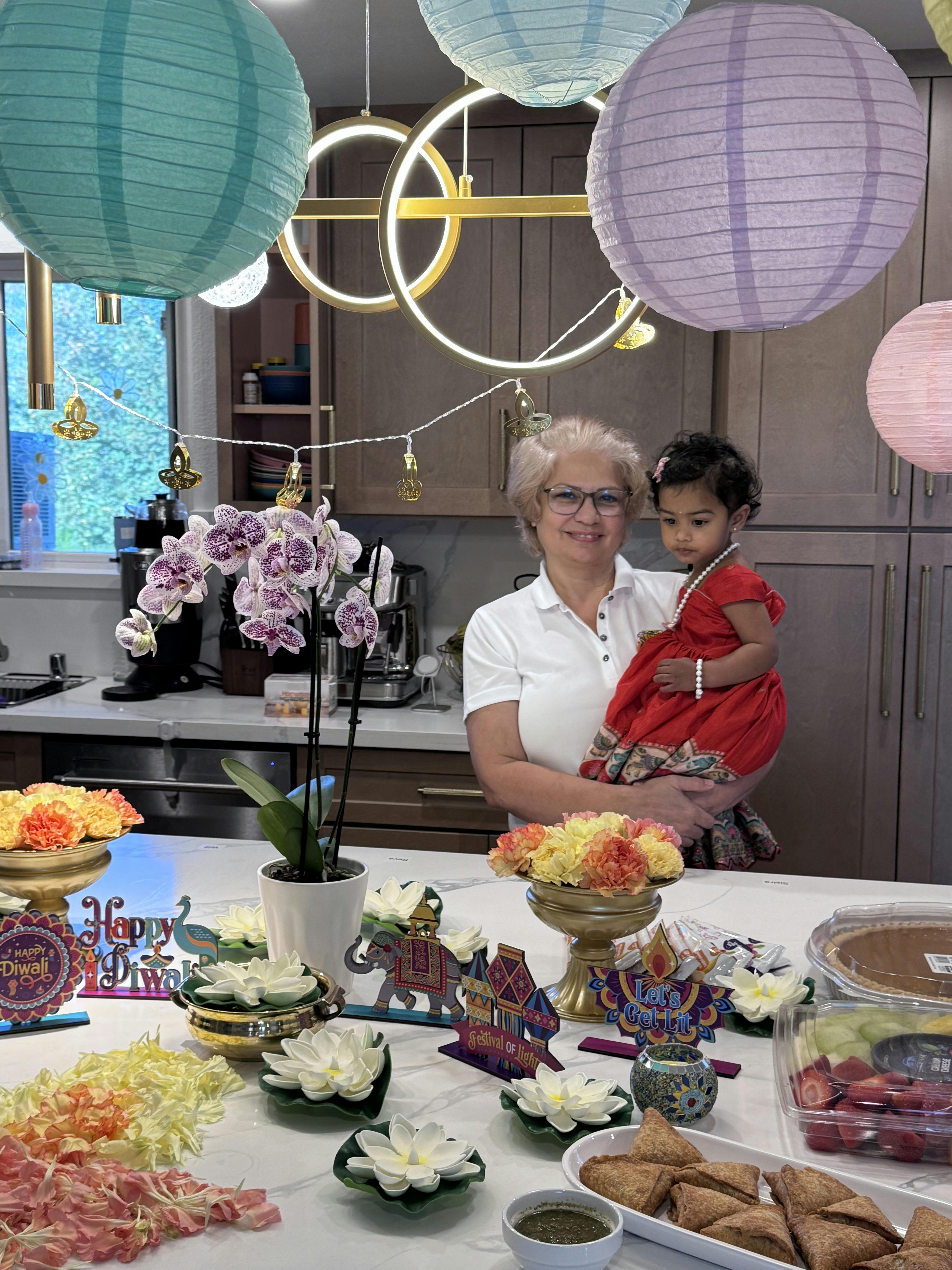 A person holding a child in a kitchen decorated for Diwali