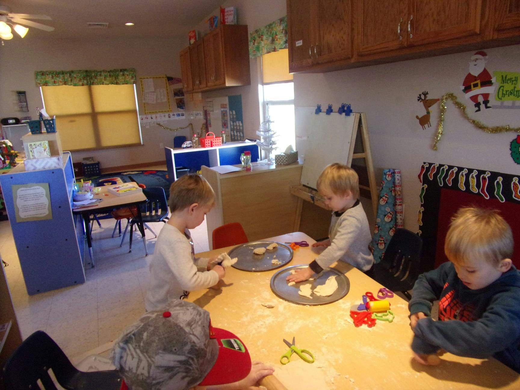 Children at a table with cookie dough and baking supplies