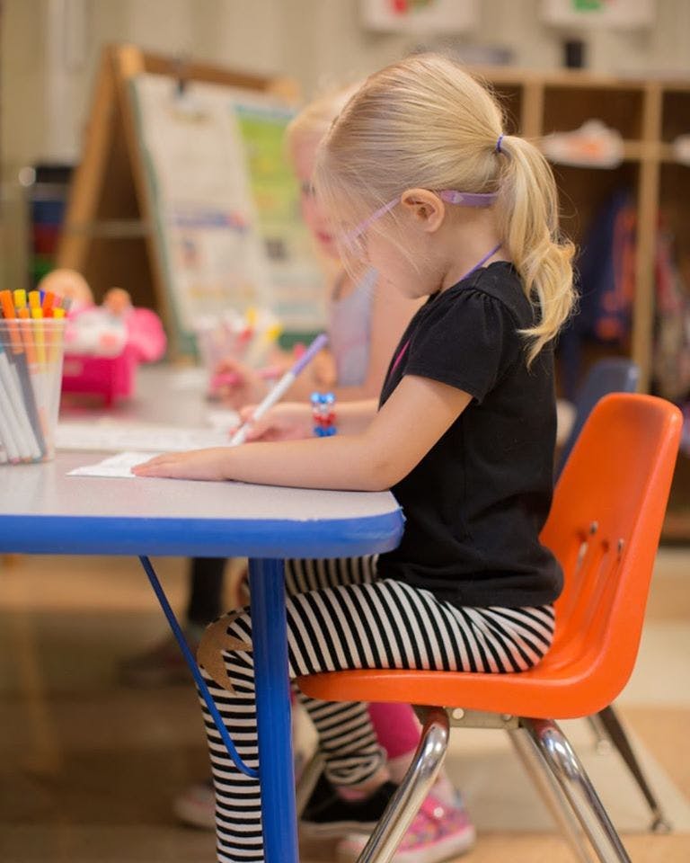 Child drawing at a table in a classroom