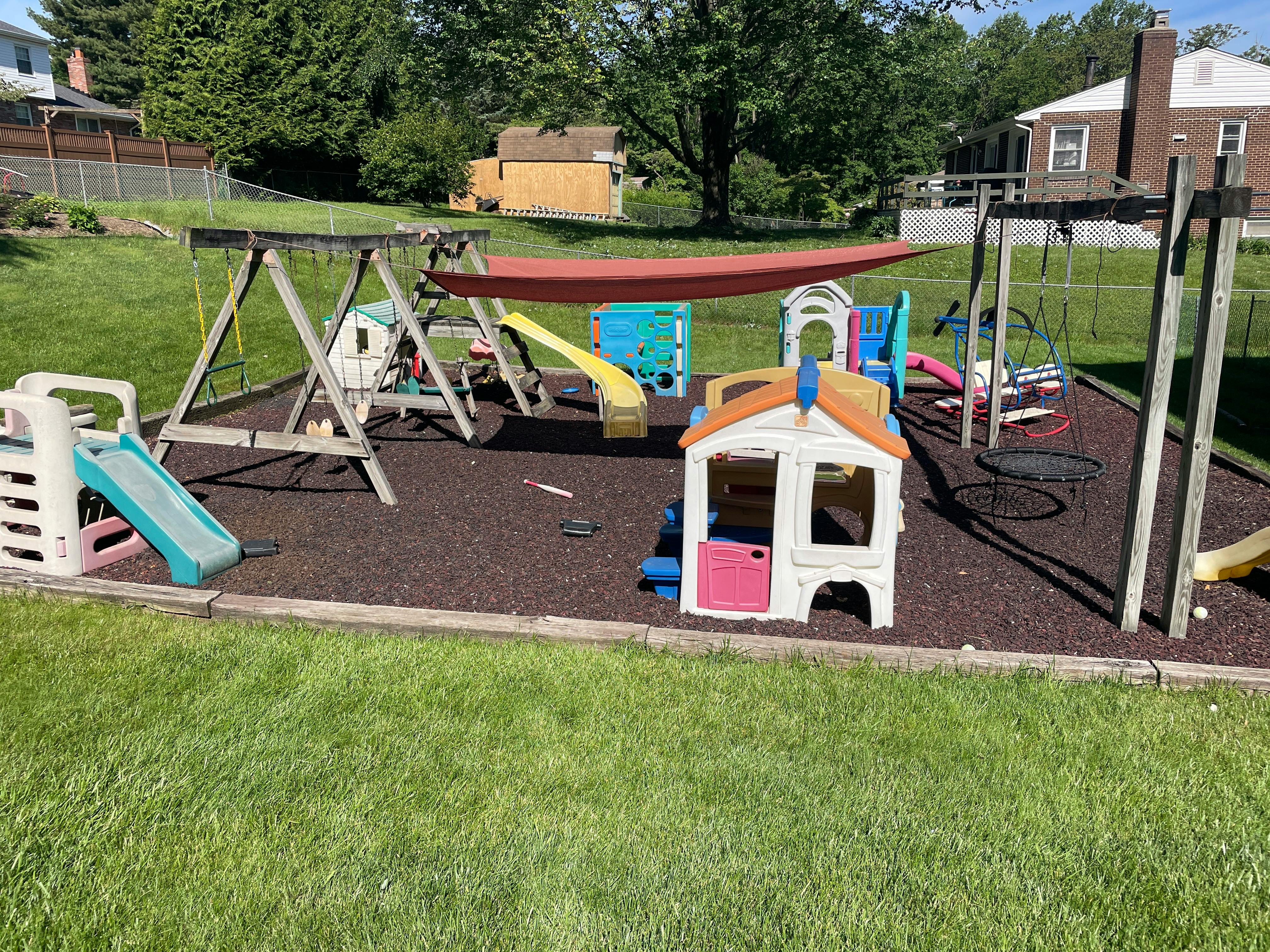Outdoor playground with swings, slides, and playhouses on wood chips