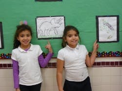 Two children pointing at drawings on a wall
