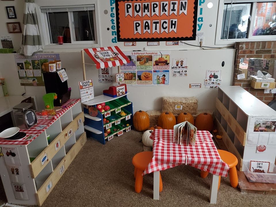 Play area with a pretend market stand, small table, and pumpkins