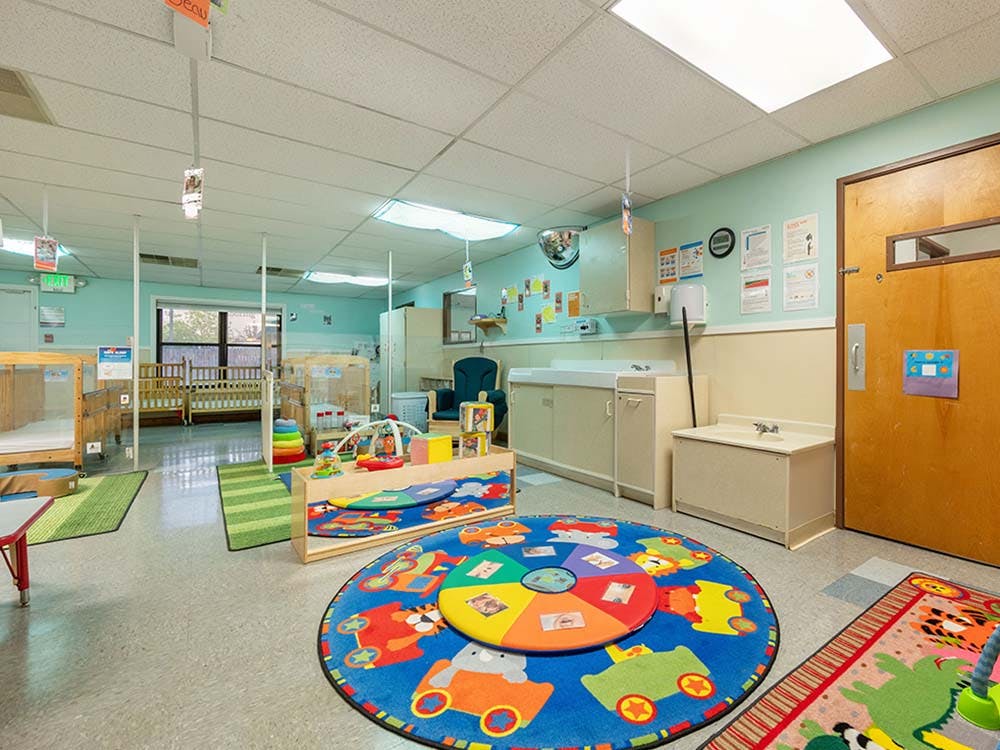 Classroom with cribs, play mats, and toys