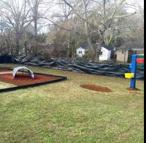 Playground with a slide and swing set next to a black fence