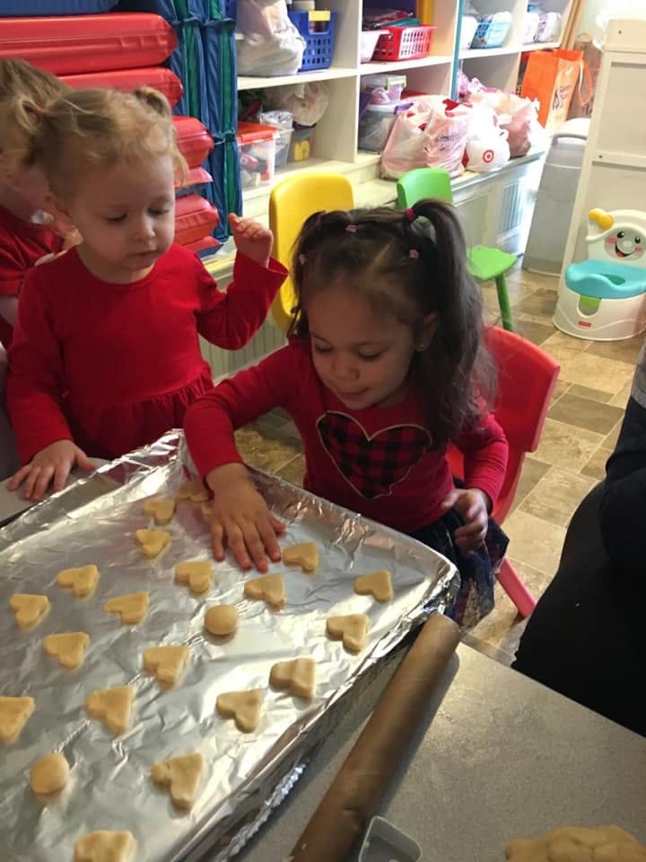 Two children placing cookie dough cutouts on a baking sheet