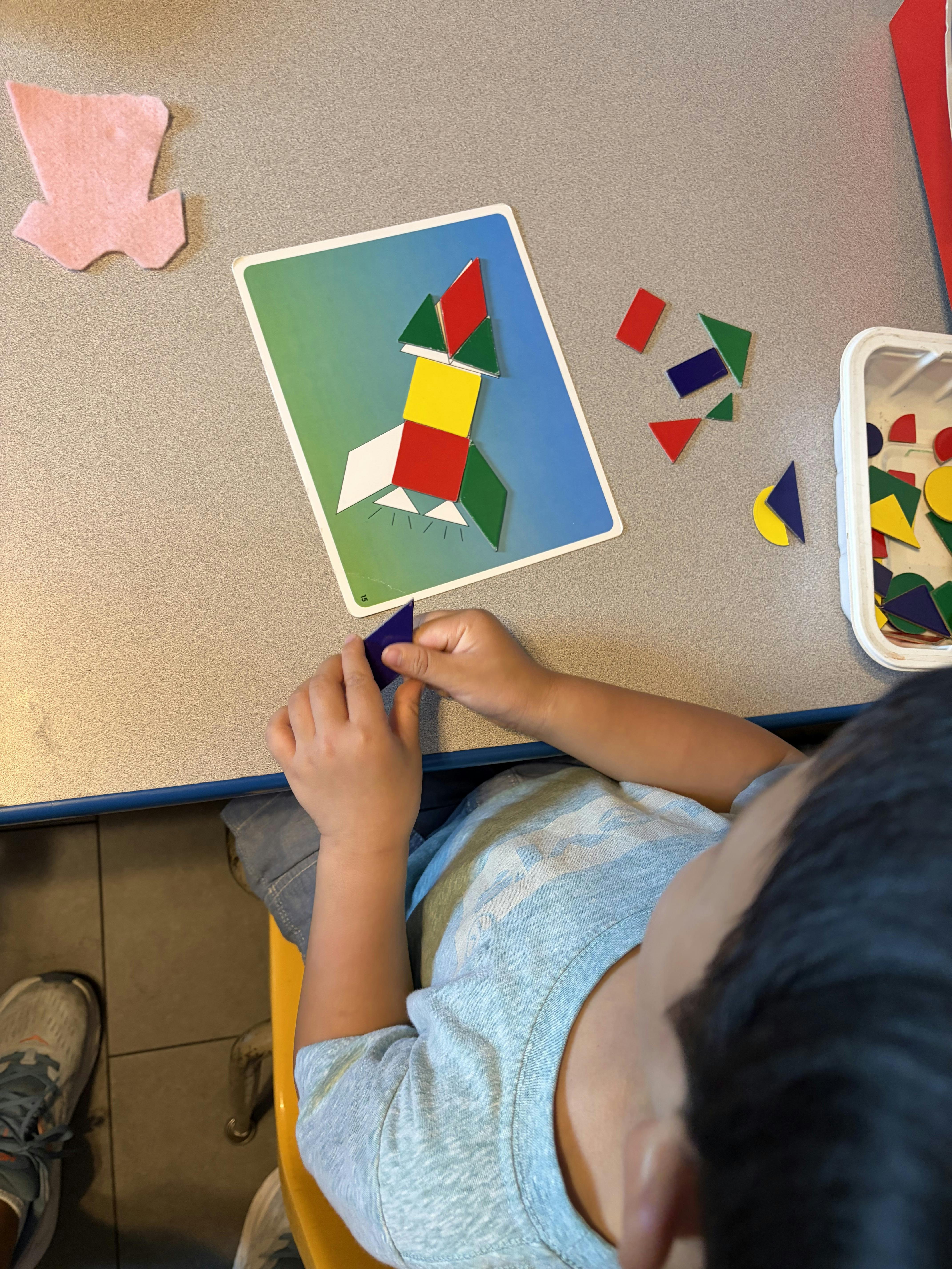 Child assembling a geometric rocket pattern on a table