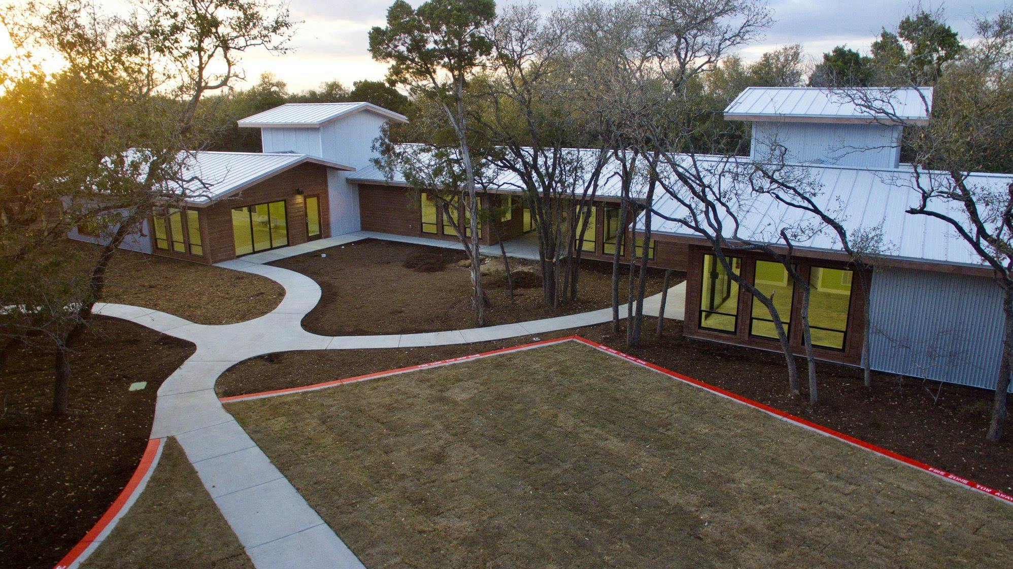 Modern building with light blue walls and yellow windows, surrounded by trees