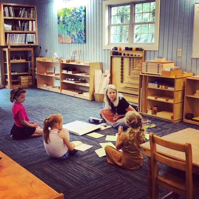 Adult and three children sitting on floor in classroom