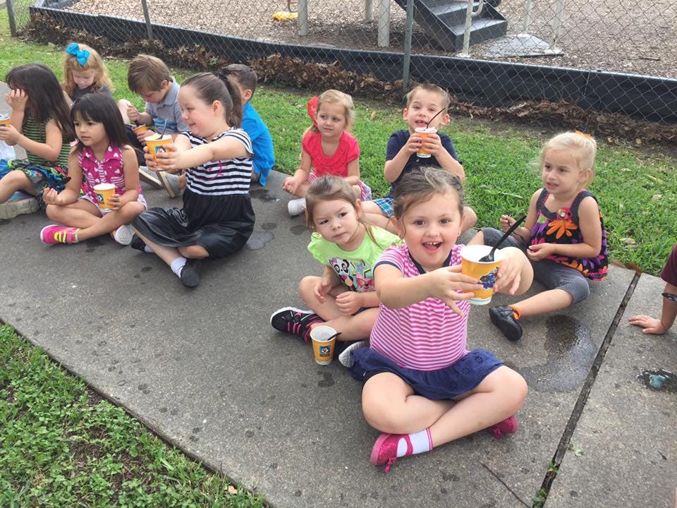 Children sitting on the ground holding cups
