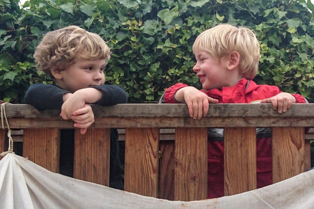 Two children looking at each other over a wooden fence