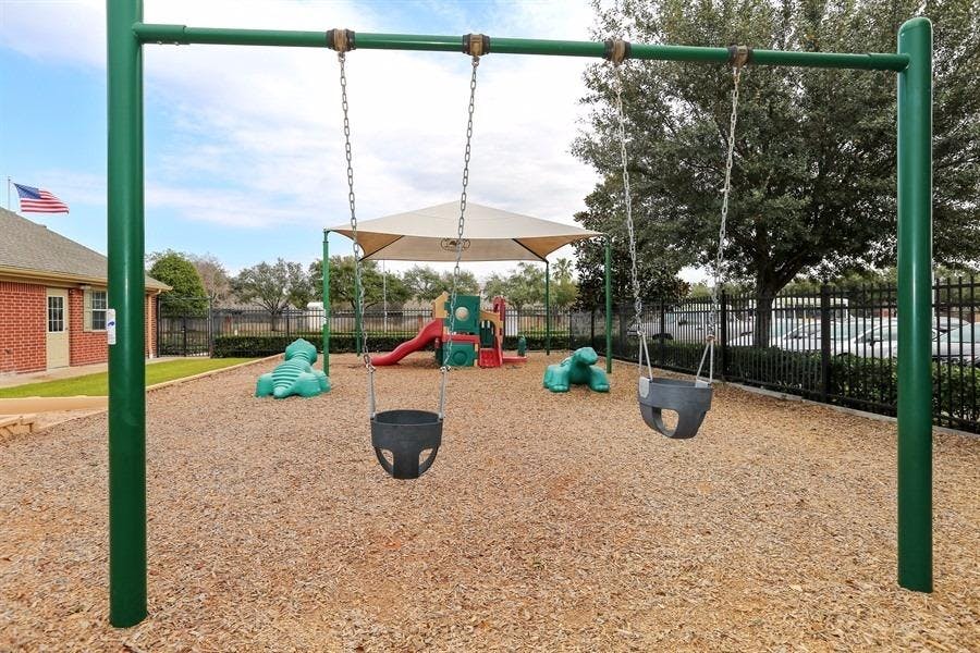 Empty swings on a playground with wood chips