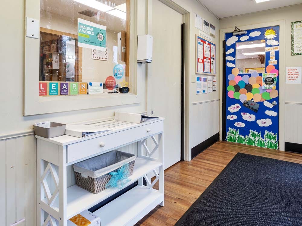 white table under a window with "LEARN" sign, decorated blue door