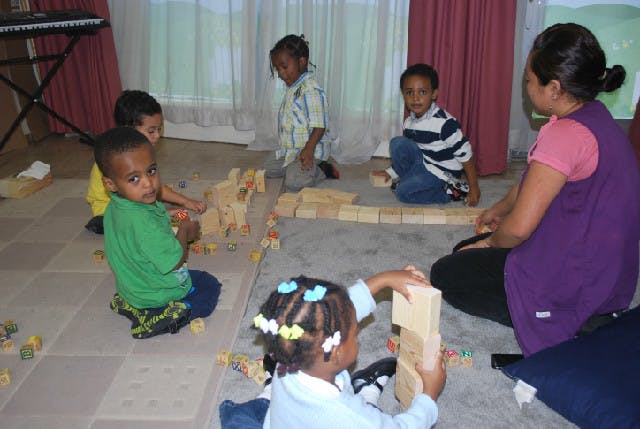 Adult and children playing with wooden blocks on the floor