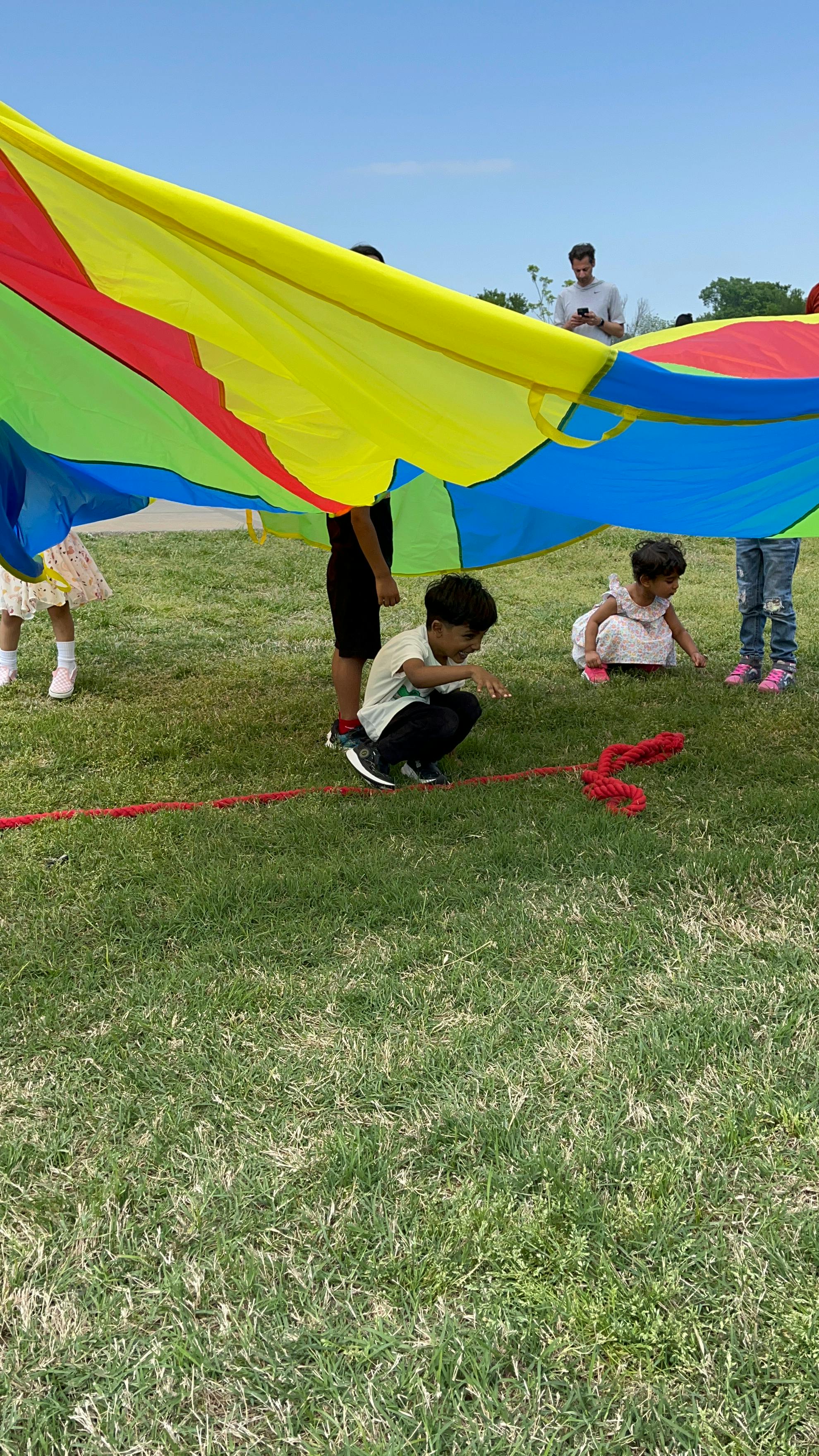 Children playing with a colorful parachute on grass