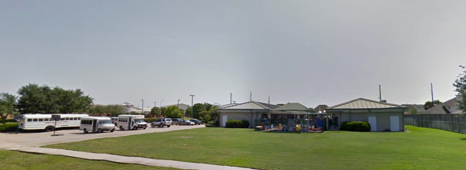 Buses and vans parked in front of a building with a green lawn
