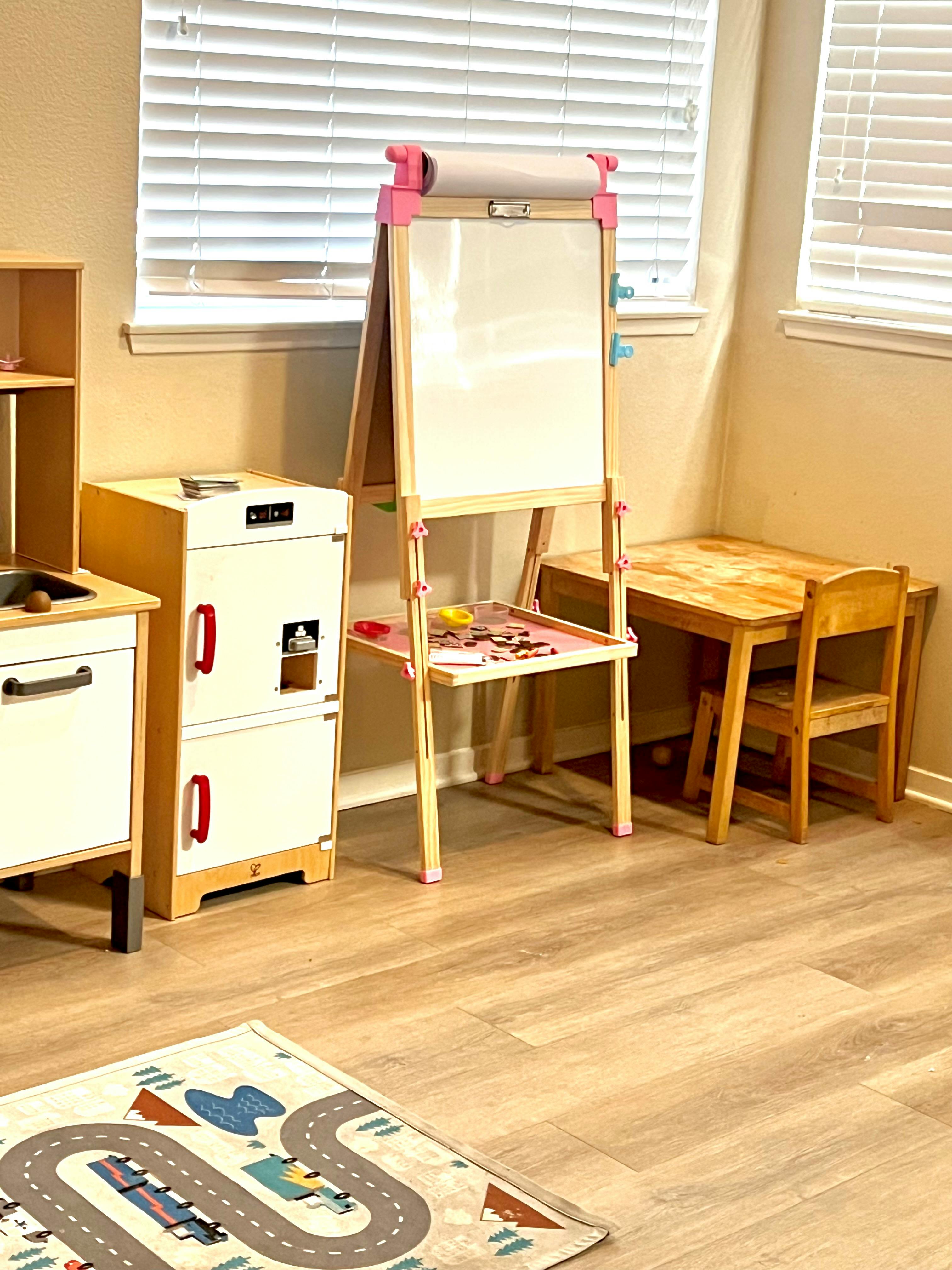 Children's play area with an easel, toy kitchen, and small table and chairs