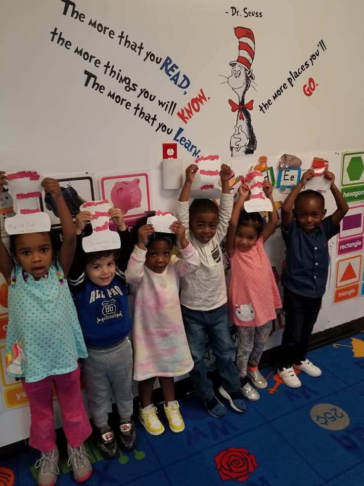 Group of children holding up paper crafts in a classroom