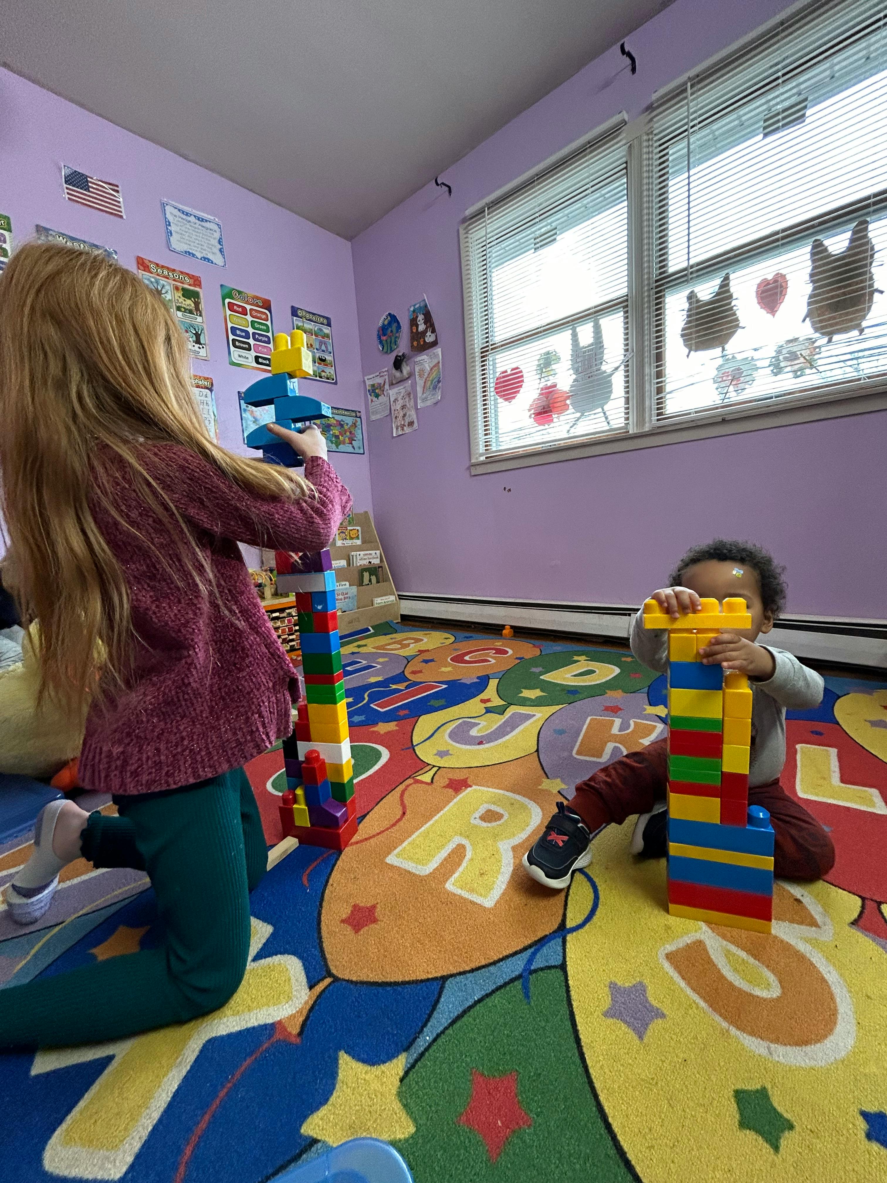 Two children playing with colorful building blocks in a classroom