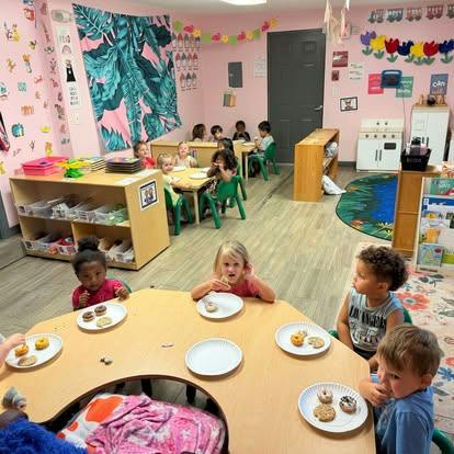 Group of children eating snacks at tables in a classroom