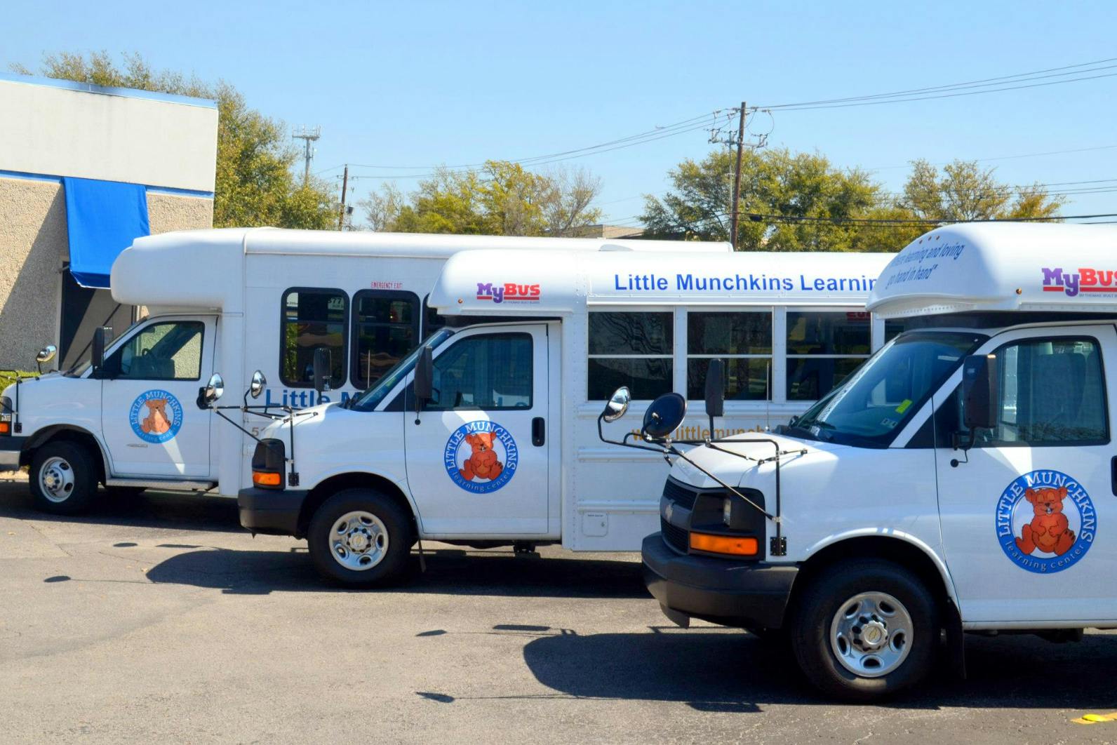 Three white shuttle buses parked in a row
