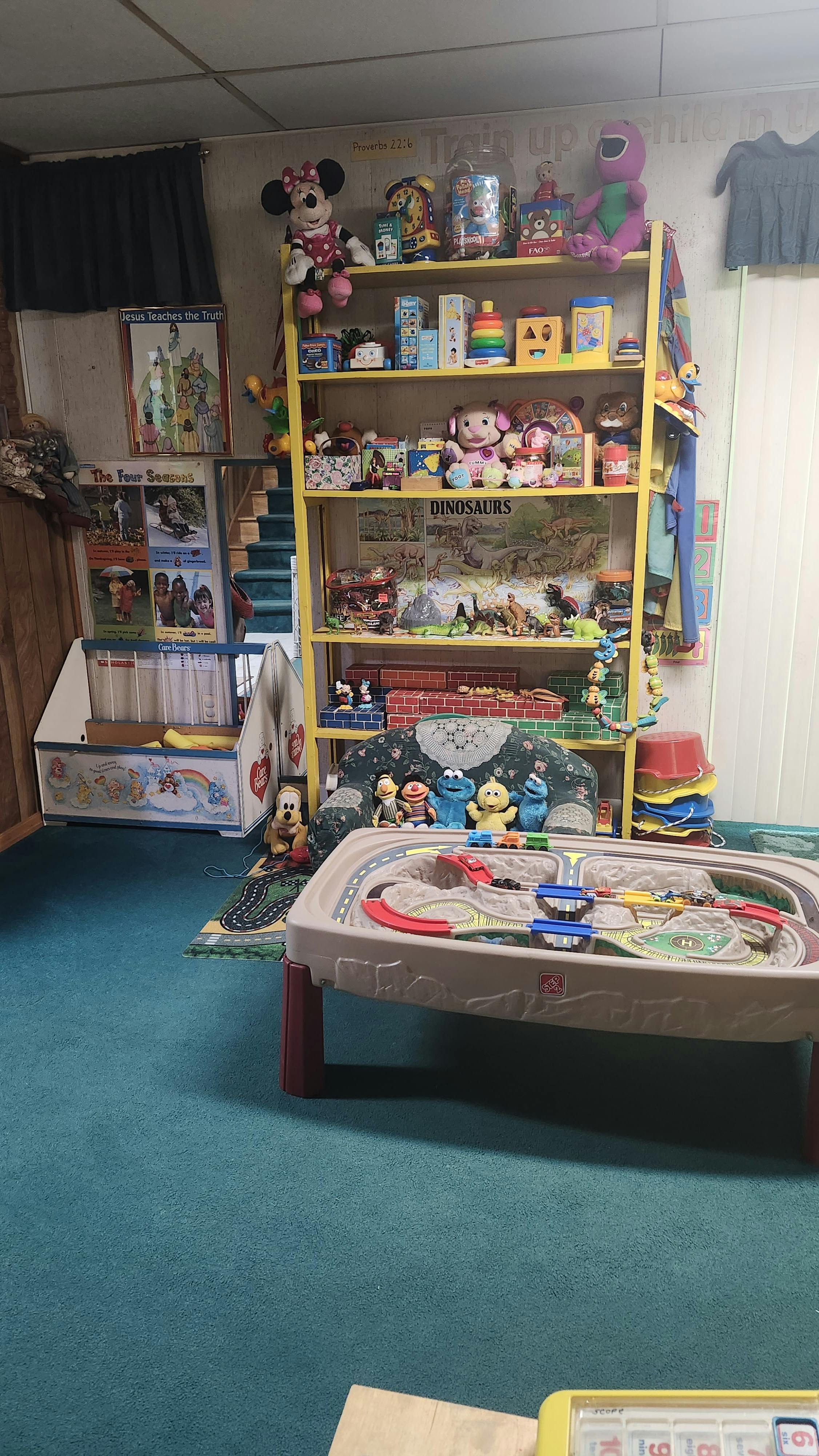 A playroom filled with a toy shelf and a train table