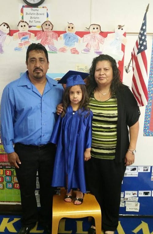 Adults with a child in a blue graduation cap and gown
