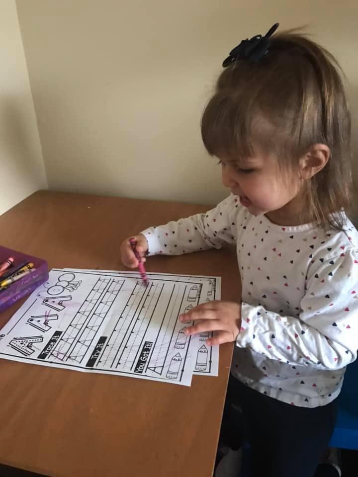 Child coloring a worksheet with the letter A